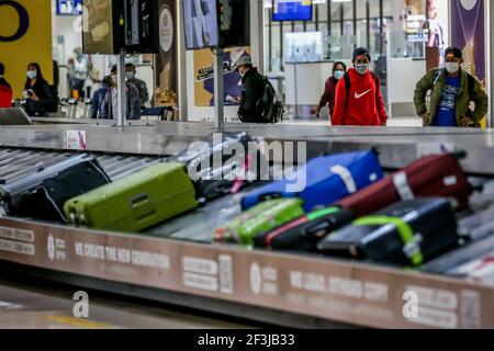 (210317) -- MANILA, 17 marzo 2021 (Xinhua) -- i passeggeri che indossano maschere protettive aspettano i loro effetti personali al carosello bagagli all'interno del Terminal 1 dell'aeroporto internazionale Ninoy Aquino di Manila, Filippine, il 17 marzo 2021. Le Filippine hanno detto che sospenderà temporaneamente l'ingresso di stranieri e di alcuni cittadini, mentre il paese del Sud-est asiatico affronta un rinnovato picco nei casi COVID-19. In una dichiarazione rilasciata il martedì sera, la task force del coronavirus del paese ha detto che i cittadini stranieri e i cittadini di ritorno che non avevano lavorato all'estero non potranno entrare nel cou Foto Stock