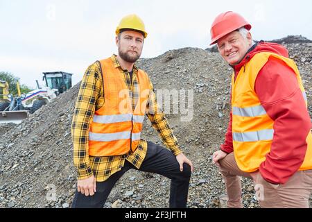 Architetto e lavoratore di costruzione si trovano di fronte a un tumulo di terra sul cantiere della casa Foto Stock