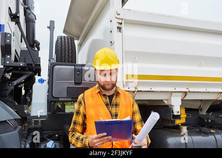 Operatore con lista di controllo per il controllo di un veicolo per la consegna durante la costruzione di strade sito Foto Stock