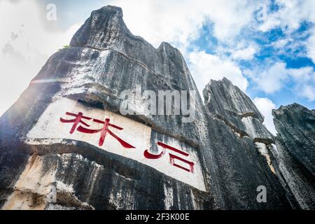 Vista panoramica della formazione calcarea scritta Shilin in caratteri cinesi rossi a Shilin Major Stone Forest Park in Yunnan Cina (traduzione: Pietra per Foto Stock