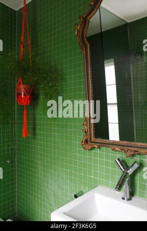 Piccolo bagno con verde smeraldo di mattonelle quadrate, dorate specchio incorniciato e ceramica rossa e corda titolare di impianto Foto Stock