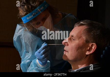 Kleinmachnow, Germania. 17 Marzo 2021. Nurse Waltraud Friese spinge un bastoncino di cotone nella narice sinistra del sindaco di Kleinmachnow Michael Grubert (SPD) durante un test a Corona. Le prove vengono effettuate nella sala cinematografica del cinema 'Neue Kammerspiele'. Sotto il motto 'basta farlo! Regione TKS tests!', i comuni di Teltow, Kleinmachnow e Stahnsdorf (distretto di Potsdam-Mittelmark) hanno costituito sette centri di test. I residenti del distretto possono prenotare un appuntamento tramite un portale Internet e ricevere i risultati via e-mail. Credit: Soeren Stache/dpa-Zentralbild/ZB/dpa/Alamy Live News Foto Stock