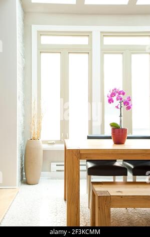 Concetto minimalista progettato con semplicità e principi zen - luminosa sala da pranzo con linee pulite, grandi finestre, luce cielo e legno di teak Foto Stock