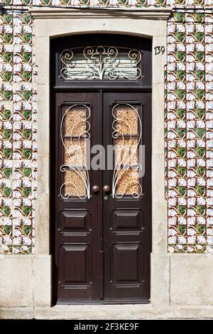 I motivi floreali dipinte su piastrelle azulejos circondano una porta tradizionale in Ilhavo, Aveiro, Portogallo Foto Stock