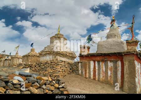 Antichi monumenti buddisti, Chortens e Stupa, con pareti in pietra a secco sotto il cielo blu nuvoloso nel villaggio himalayano di Tashigang, Himachal Pradeesh, India. Foto Stock