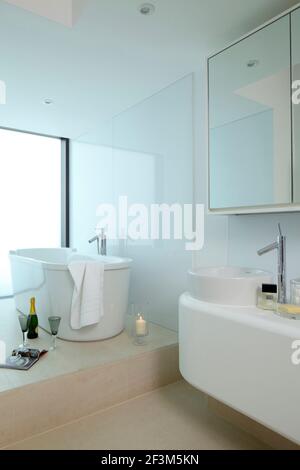 Bagno sulla piattaforma rialzata con bottiglia di champagne, bicchieri e candela in UK show home Foto Stock