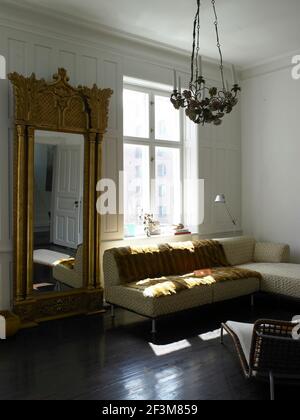 Soggiorno con grande specchio incorniciato dorato e divano ad angolo in casa residenziale, Danimarca Foto Stock