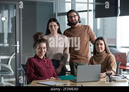 Ritratto del team aziendale di successo che sorride alla fotocamera mentre lavora in team insieme in ufficio Foto Stock