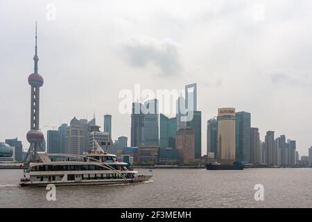 Shanghai, Cina - 4 maggio 2010: Traghetto passeggeri sul fiume di fronte allo skyline di Pudong sotto il paesaggio color argento. Edifici iconici e moderni per uffici e Pearl T. Foto Stock