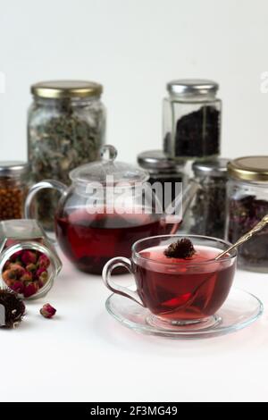 Tè alle erbe fatto in casa. Un rimedio che aumenta l'immunità e allevia lo stress. Teiera in vetro e tè con una bevanda sana. Vasi trasparenti con erbe secche Foto Stock