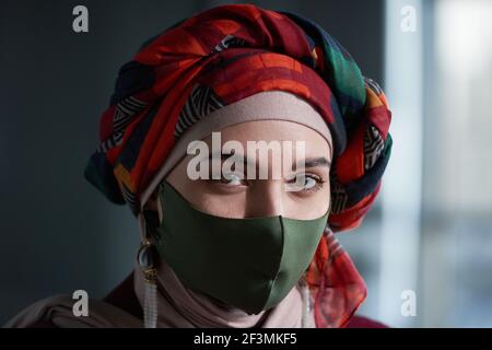 Ritratto di donna musulmana in bella sciarpa sulla testa e maschera protettiva che guarda la fotocamera Foto Stock