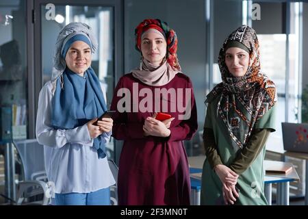 Ritratto di tre donne in hijabs guardando la macchina fotografica mentre stare insieme in ufficio Foto Stock
