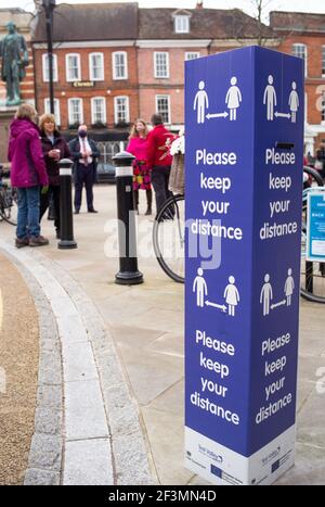 Distanza sociale mantenere la vostra distanza segni nella città mercato di Romsey Hampshire Inghilterra e le persone che si incontrano per il caffè nella piazza della città. Foto Stock