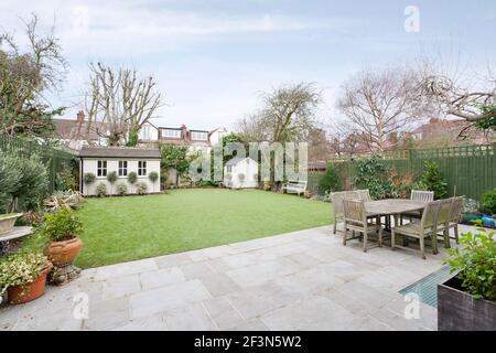 Grande casa di famiglia a Wandsworth, con seminterrato e cucina a pianta aperta estensione. Patio giardino con mobili e vista sul prato Foto Stock