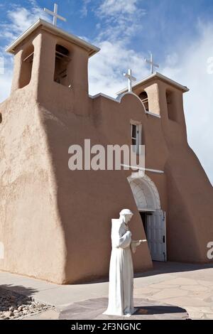 La statua di San Francesco fuori dall'ingresso principale della chiesa di San Francesco, Ranchos de Taos, New Mexico, USA. (L'iconica chiesa ha ispirato l'arte Foto Stock