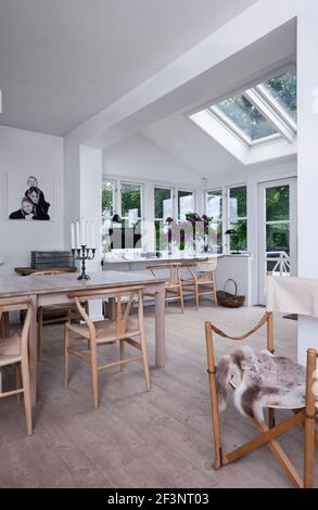 Luminoso, accogliente e confortevole, in Scandinavia. Un piano aperto e una stanza con grandi vetrate e un tavolo da pranzo e sedie. Foto Stock