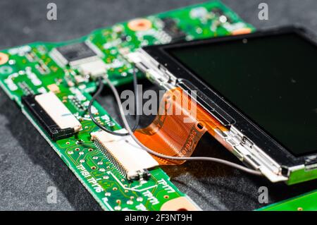 Scheda elettronica verde con un monitor collegato attraverso un piano cavo a nastro per il collegamento di un chip Foto Stock