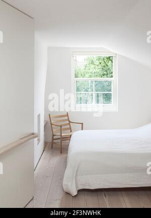 James Wright della casa di Macdonald Wright Architects a Londra. Una camera da letto minimalista al piano superiore con linee interessanti che seguono la forma del buil Foto Stock