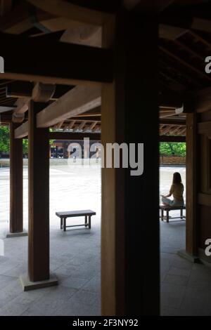 Un visitatore medita all'interno del santuario centrale del Santuario Meiji-Jingu, situato nel quartiere Shibuya di Tokyo, Giappone. Foto Stock