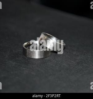 Anelli di nozze su una superficie scura. Decorata in modo unico con impronte digitali lascate e un diamante Foto Stock