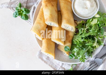 Crepes salato o frittelle sottili con pollo servito con insalata verde e salsa di bechamel. Messa a fuoco selettiva. Foto Stock