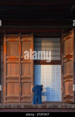 Una vista nel tardo pomeriggio mostra un giovane monaco che chiude le grandi porte di legno che circondano la sala principale di Hondo di Chion-in, un tempio buddista situato nel Th Foto Stock