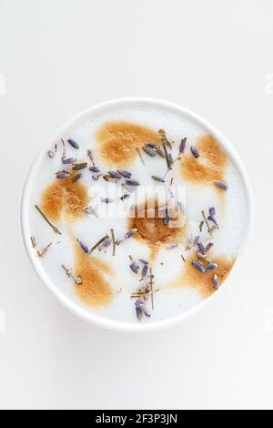 Tazza di cappuccino lavanda, piatto, vista dall'alto. Splendido latte di speculos con una schiuma di latte in un bicchiere di papà, decorato con lavanda. Foto Stock