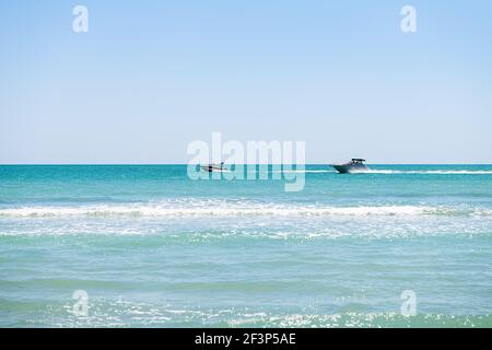 Bowman's Beach nell'isola di Sanibel, Florida, con due barche a motore bianche che cavalcano sulle colorate acque turchesi del Golfo del Messico in un giorno di sole Foto Stock