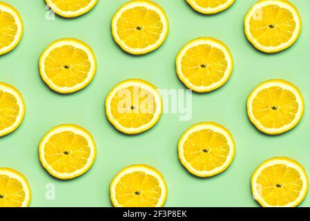 Vista dall'alto del motivo creativo fatto di fette di limoni uno sfondo verde pastello Foto Stock