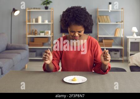 Donna afroamericana con disgustosa rimata guardando un pezzo di mela sulla piastra Foto Stock