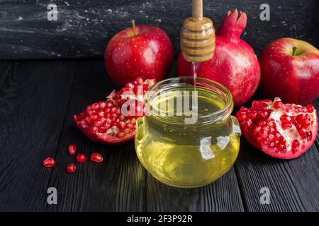 Primo piano su miele, melograno e mele rosse su fondo nero Foto Stock