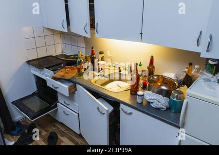 Cucina disordinata dopo la festa. Bottiglie di birra, piatti in lavandino, bottiglia di vino Foto Stock