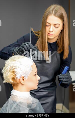 Donna parrucchieri tintura capelli di giovane donna caucasica in capelli salone Foto Stock