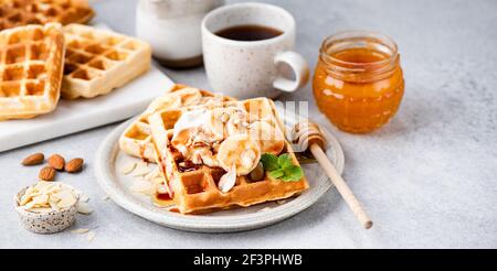 Cialde belghe dolci con salsa di banana e caramello su un piatto. La colazione comprende waffle e caffè Foto Stock