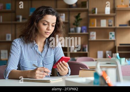 Ispanico latino ragazza studente universitario tenere smartphone studiare in università. Foto Stock