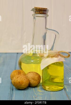 olio di noce in bottiglia di vetro su fondo di legno blu Foto Stock
