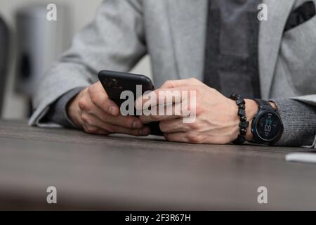 vista parziale di uomo d'affari con le mani in serratura seduto al tavolo, concetto di business, orologio da polso Foto Stock