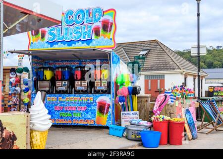 Una stalla che offre da servire-te ghiaccio-freddo schiush sul lungomare, così come reti da pesca e altri giocattoli da spiaggia, Westward ho!, Devon, Regno Unito Foto Stock