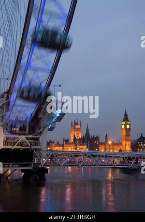 Vista sul Tamigi, che mostra la ruota del London Eye in primo piano e le Houses of Parliament illuminate, Londra, Regno Unito. Foto Stock