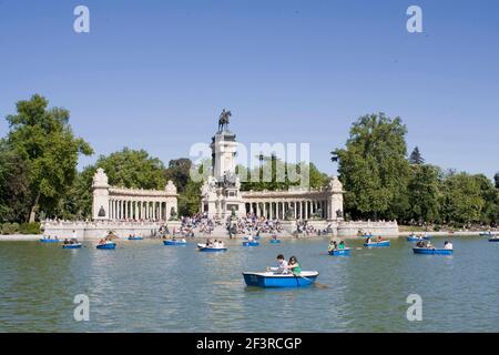 Persone in barca su un lago artificiale di fronte al monumento ad Alfonso XII, Buen Retiro Park, Madrid, Spagna. Foto Stock