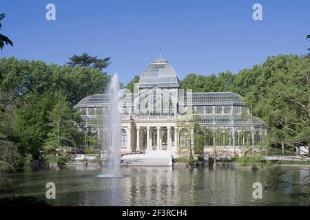 Vista sul lago fino al Palacio de Cristal, o Palazzo Cristallo, progettato dall'architetto Ricardo Velazquez Bosco (1887), Parco Buen Retiro, Madrid, Spagna. Foto Stock