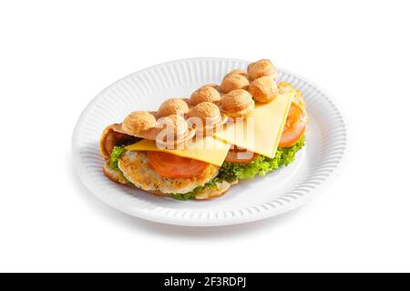 Waffle a bolle d'aria di Hong Kong. Farcire la cialda con formaggio, pollo fritto, pomodoro e insalata su un piatto di carta isolato su sfondo bianco. Foto Stock