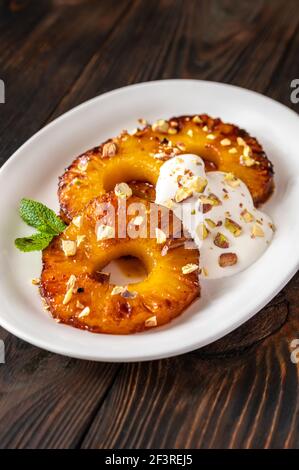 Ananas caramellato con panna montata e pistacchi sul piatto piastra Foto Stock