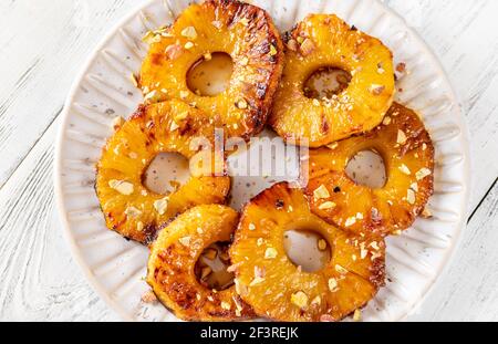 Ananas caramellato con panna montata e pistacchi sul piatto piastra Foto Stock