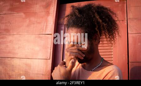 Triste uomo nero. Lunghi capelli ricci su un giovane di etnia brasiliana. Concetto di tristezza pandemica e ansia. Uomo bearded Foto Stock