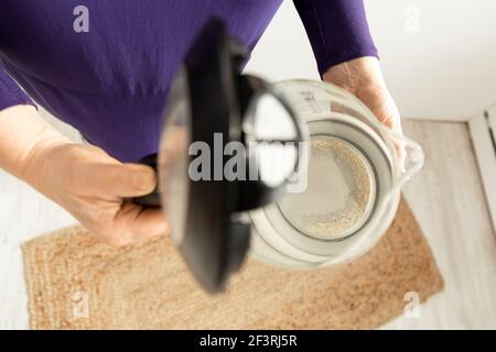 Donna mani bollitore con calcare. Un residuo bianco di carbonato di calcio. Riparazione di elettrodomestici causata da acqua dura Foto Stock