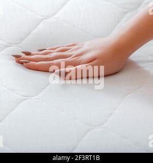 Scelta di comodi materassi per dormire in negozio. Controllo qualità durezza materasso bianco. Donna che sceglie il nuovo materasso. Prova di pressatura manuale femmina Foto Stock
