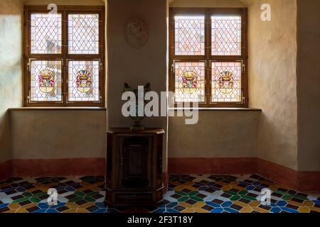 Interni della camera del Castello di Bauska Duke con finestre in vetro, pavimento colorato e vaso antico su armadio d'epoca Foto Stock