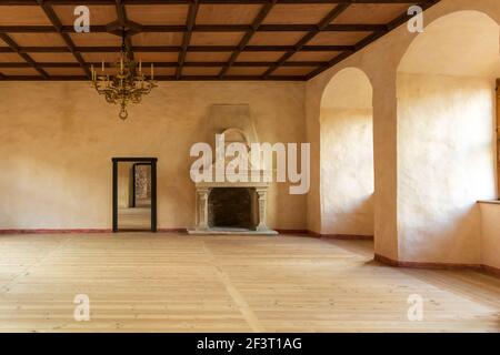 Castello di Bauska - Grande Sala di celebrazioni con pavimento in legno, candelabro dorato, e camino con sculture in pietra Foto Stock