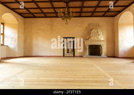 Castello di Bauska - Grande Sala di celebrazioni con pavimento in legno, candelabro dorato, e camino con sculture in pietra Foto Stock